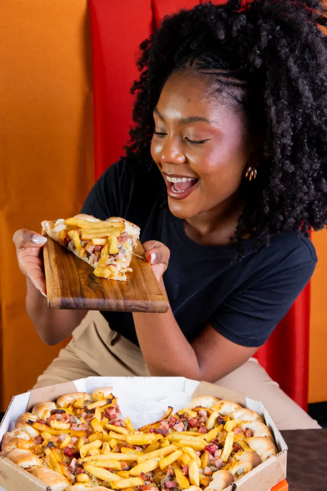 Cliente sorrindo com um pedaço de pizza
